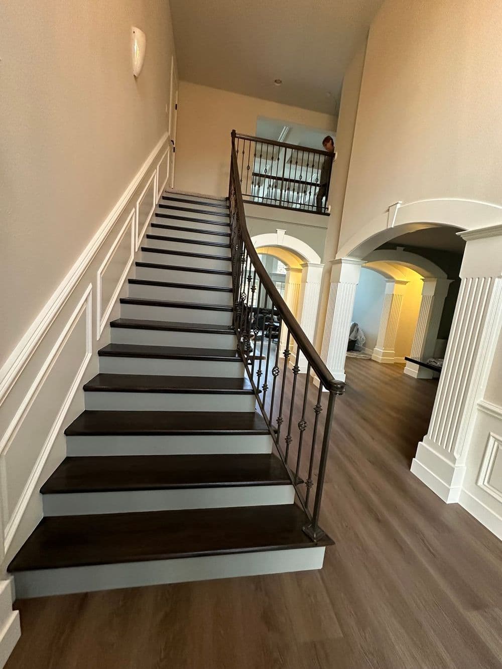 Elegant curved staircase with dark wooden steps and decorative iron railing in a spacious hallway.