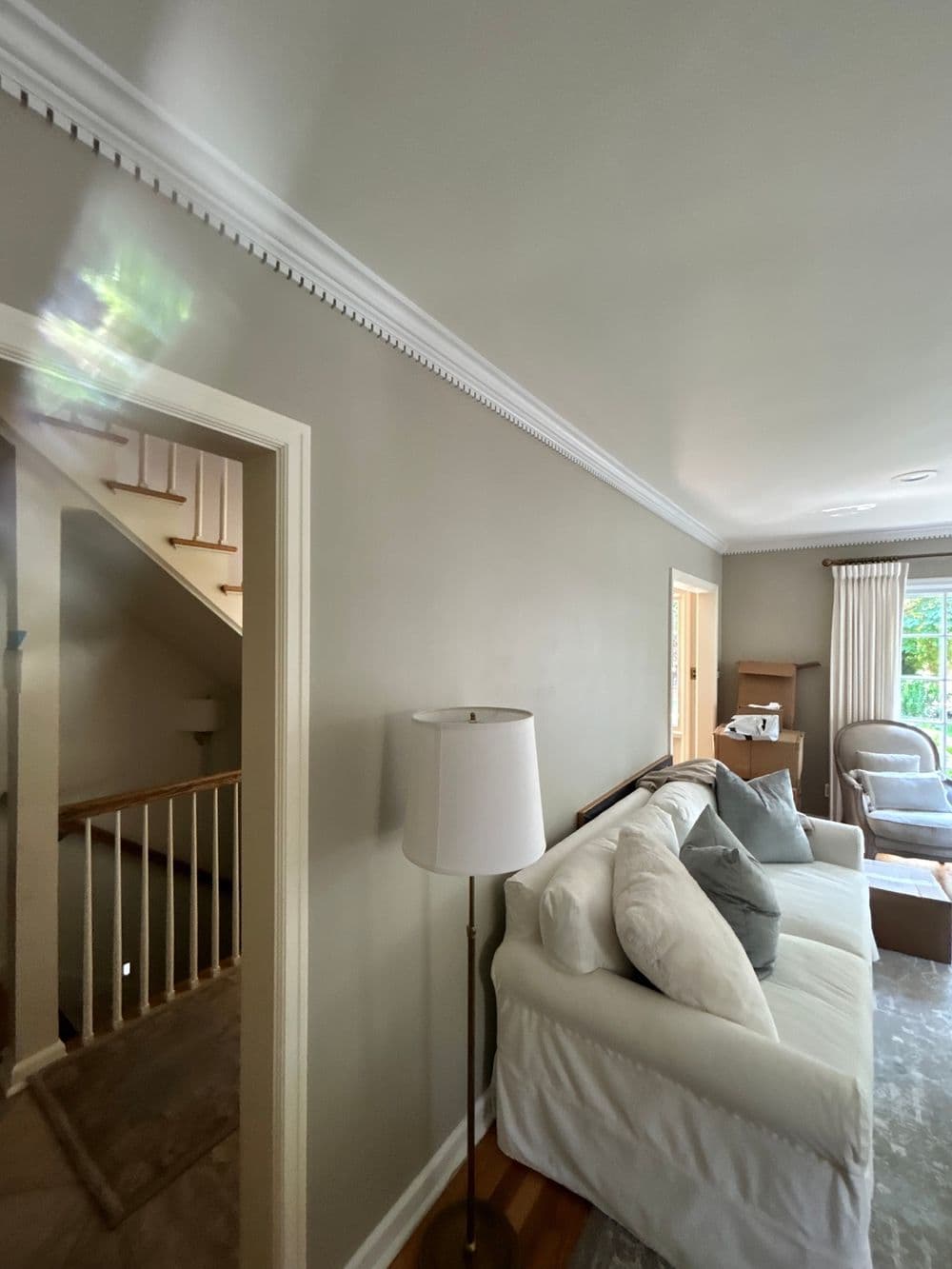 Cozy living room with cream sofa, lamp, and staircase leading to upper level.