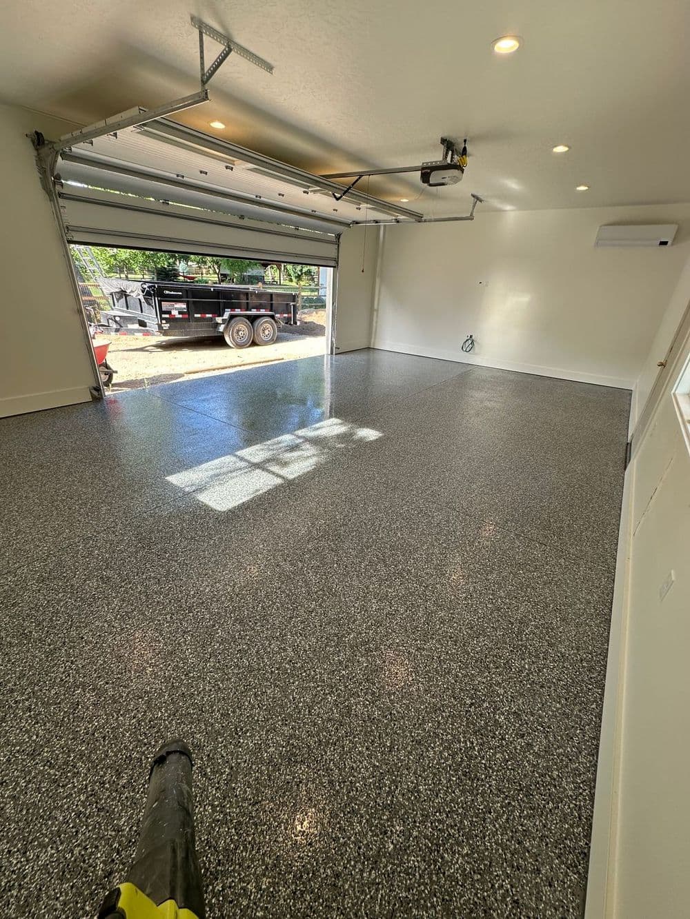 Spacious, newly finished garage with polished floor and open door allowing natural light.