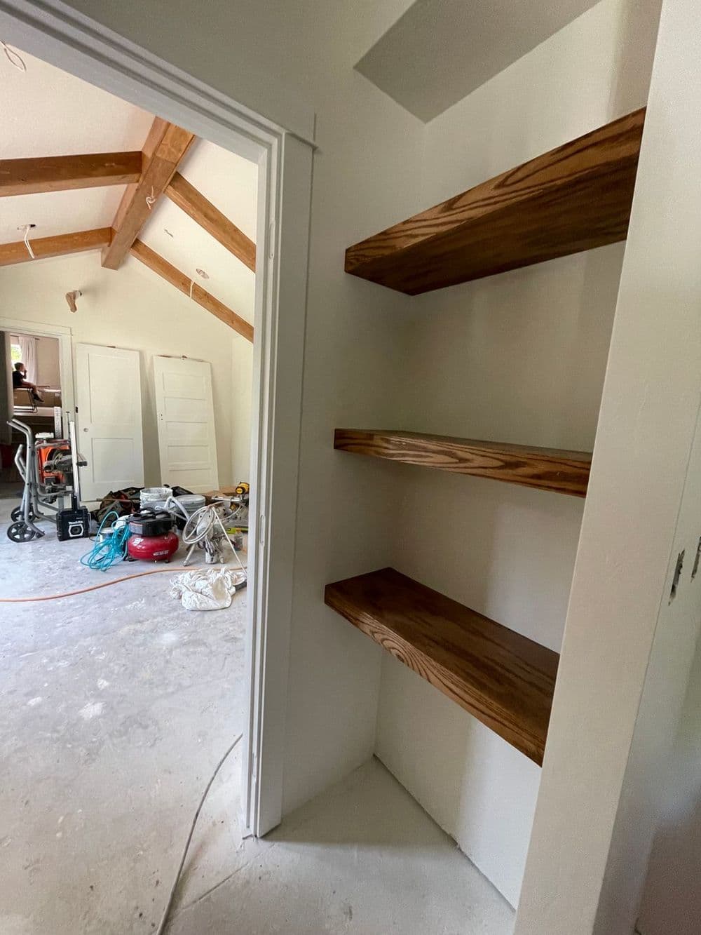 Interior view of a room with unfinished walls and wooden shelves in a closet.