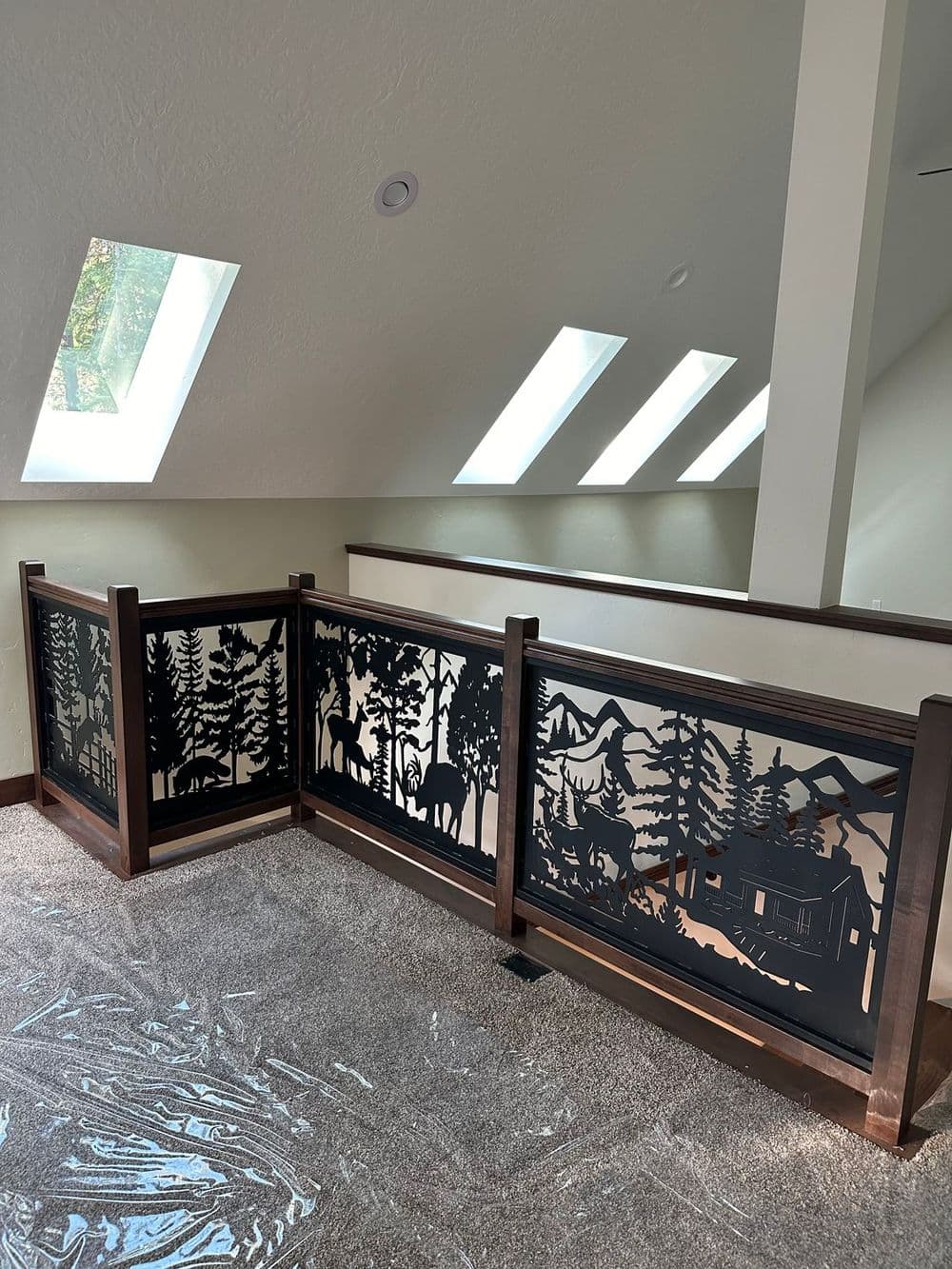 Decorative wooden railing with scenic forest and wildlife metal cutouts in an attic space.