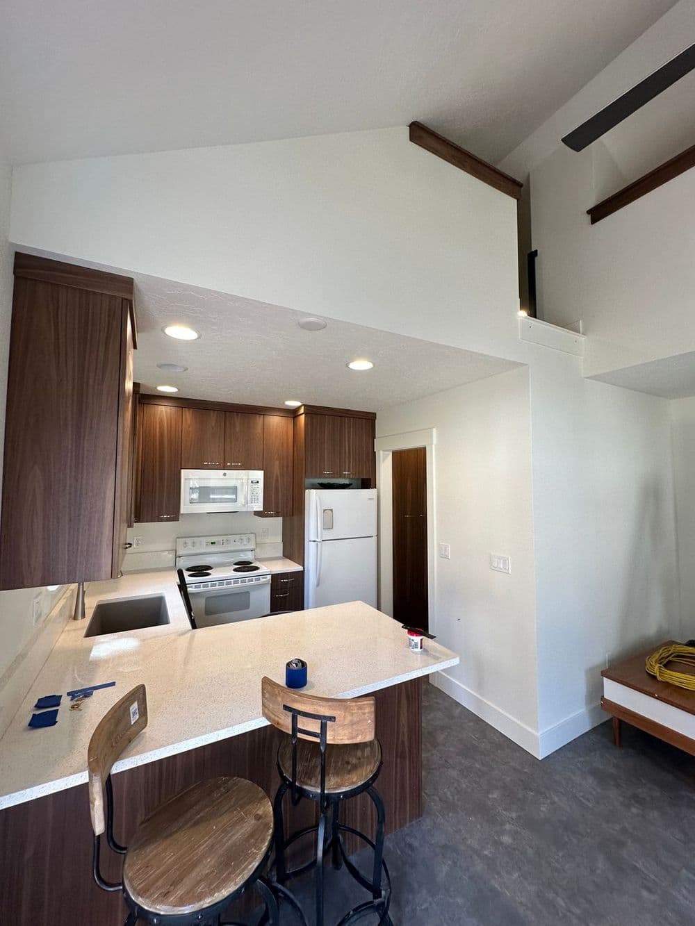 Modern kitchen with wooden cabinets, white appliances, and a lofted ceiling design.