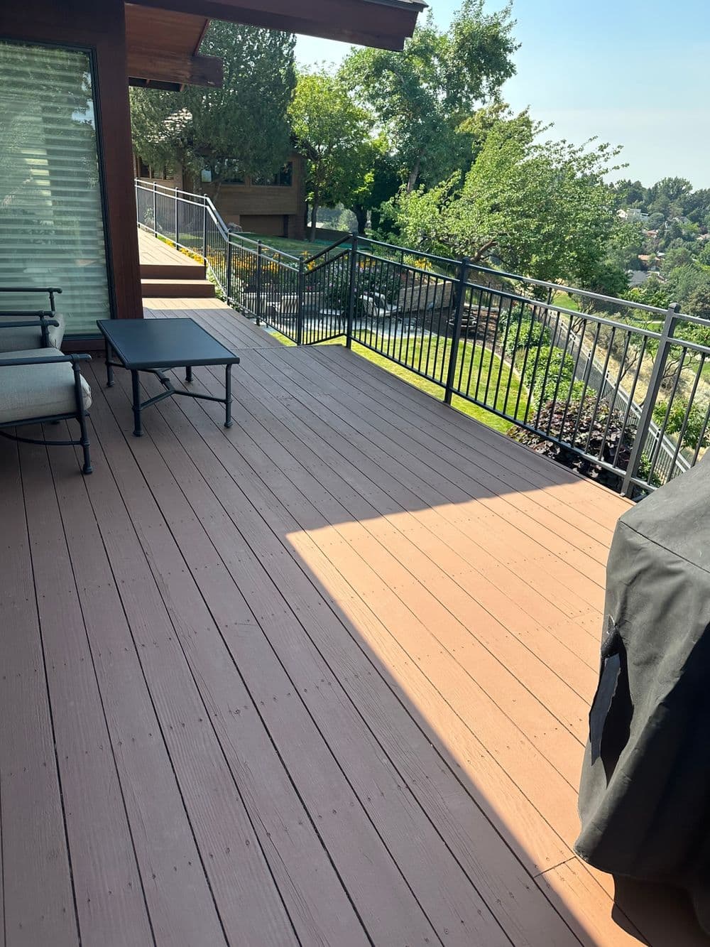 Spacious wooden deck with grill and seating, overlooking a lush green landscape.