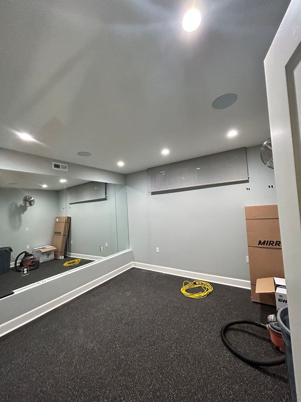 Empty modern room with gray walls, mirror, and lighting, ready for design or renovation.