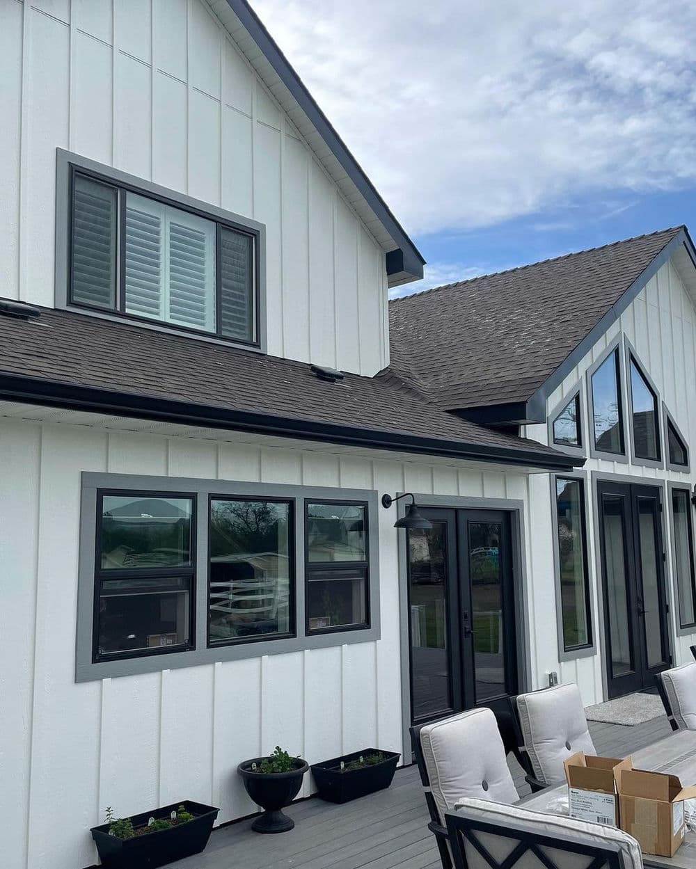 Modern white house exterior with gray accents and large windows, featuring a spacious deck.